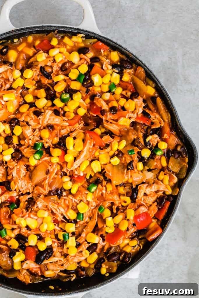 Cheesy Chicken Enchilada Delight 6 A hearty chicken casserole, rich with corn and other vegetables, simmering in a large skillet, ready for assembly into a baking dish.