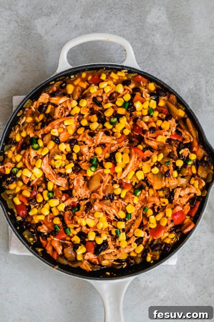 Cheesy Chicken Enchilada Delight 7 A large skillet brimming with a rich and hearty Chicken Enchilada Casserole, showcasing the generous filling and saucy texture.