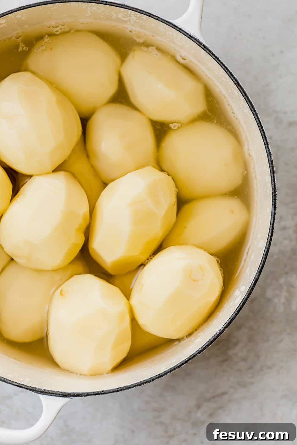 Fresh Russet potatoes in a large pot, ready for boiling.