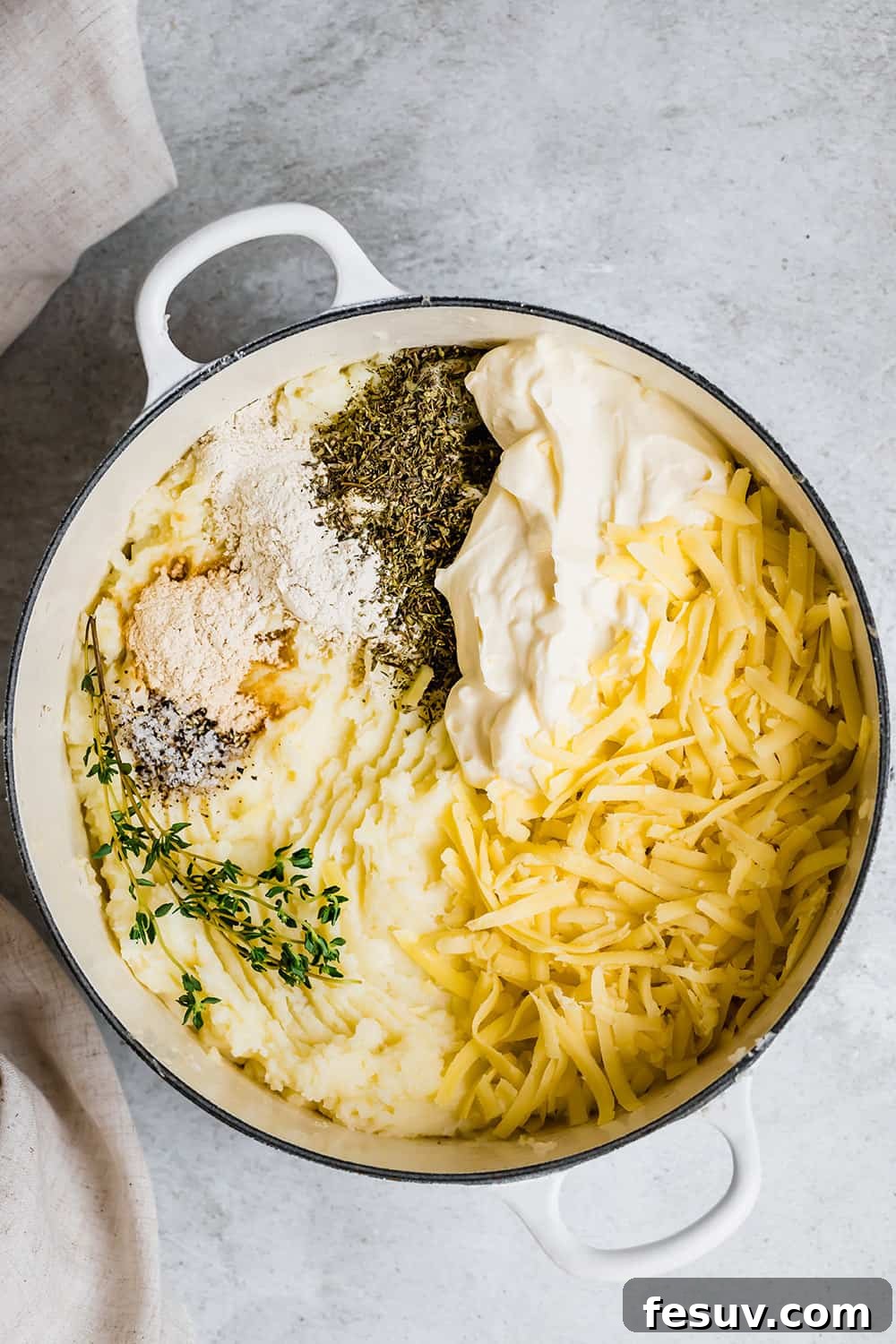All the ingredients for baked mashed potatoes arranged around a pot, ready to be mixed together.