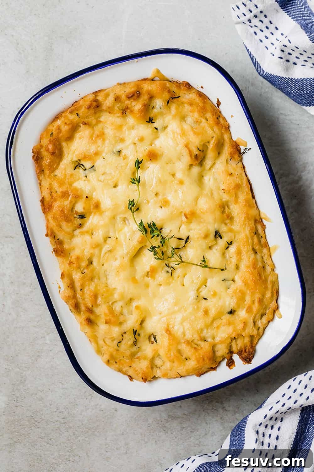 A beautifully golden-brown baked mashed potato casserole in a white dish, fresh out of the oven.