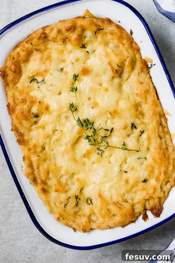Overhead shot of creamy baked mashed potatoes in a white baking dish, garnished with fresh chives.