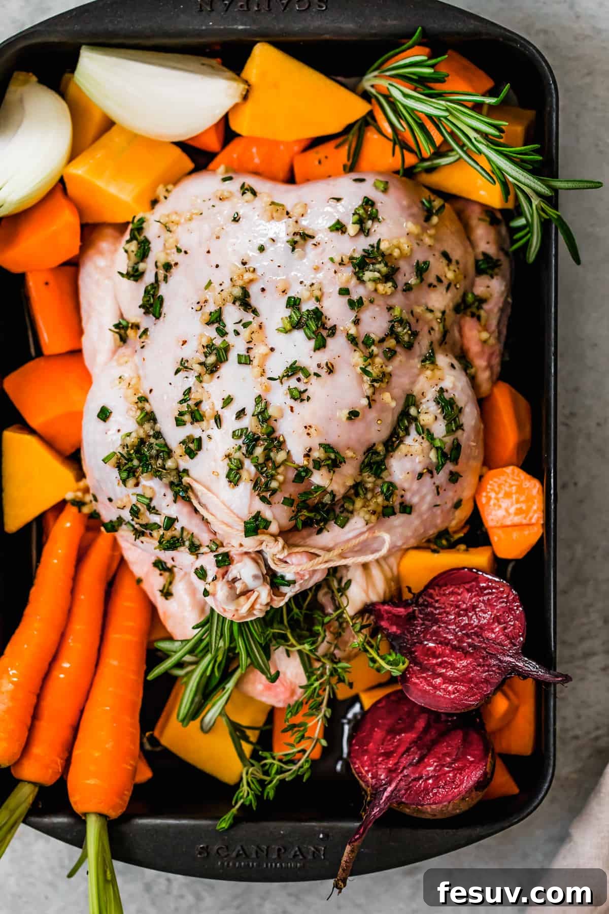 Golden Autumn Roast Chicken with Rustic Root Vegetables 5 Whole raw broiler chicken with root vegetables in a baking pan before roasting.