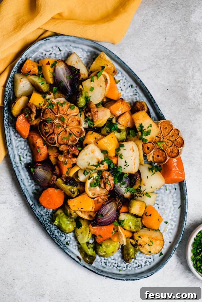 A vibrant medley of golden-brown roasted vegetables, including brussels sprouts, butternut squash, potatoes, and garlic, arranged artfully on a blue serving platter, garnished with fresh herbs and lemon slices.