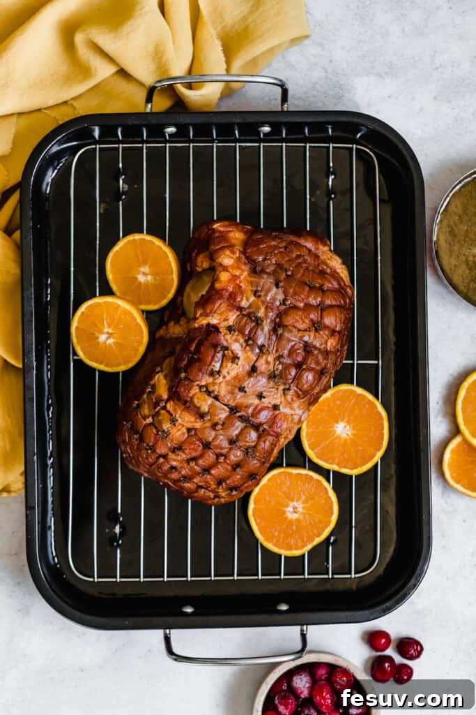 A Christmas Ham on a Roasting Pan with Four Orange Slices, ready for baking.