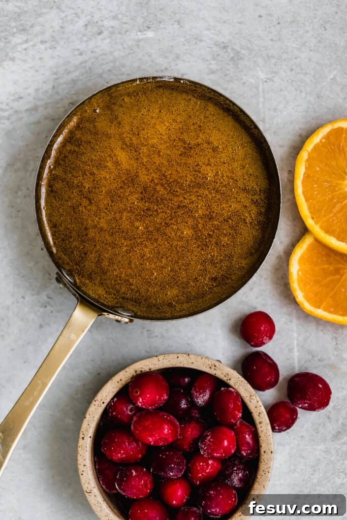 A Pan Filled with Homemade Brown Sugar Glaze Beside a Bowl of Fruit, showing the rich, thick glaze.
