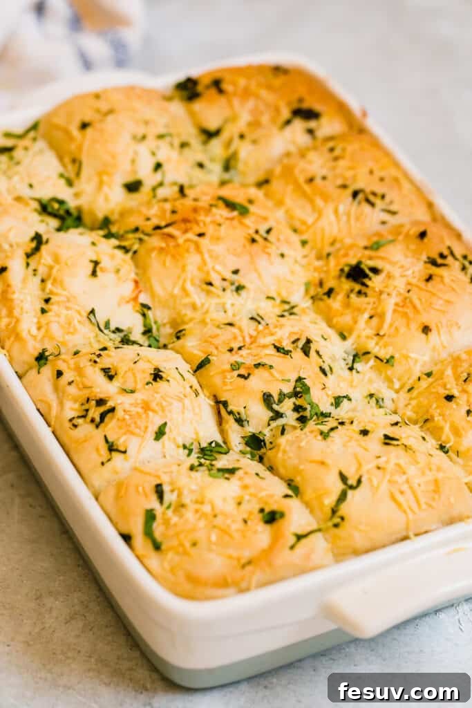 A close-up view of golden-brown Soft Parmesan Dinner Rolls nestled together in a baking pan, ready to be served