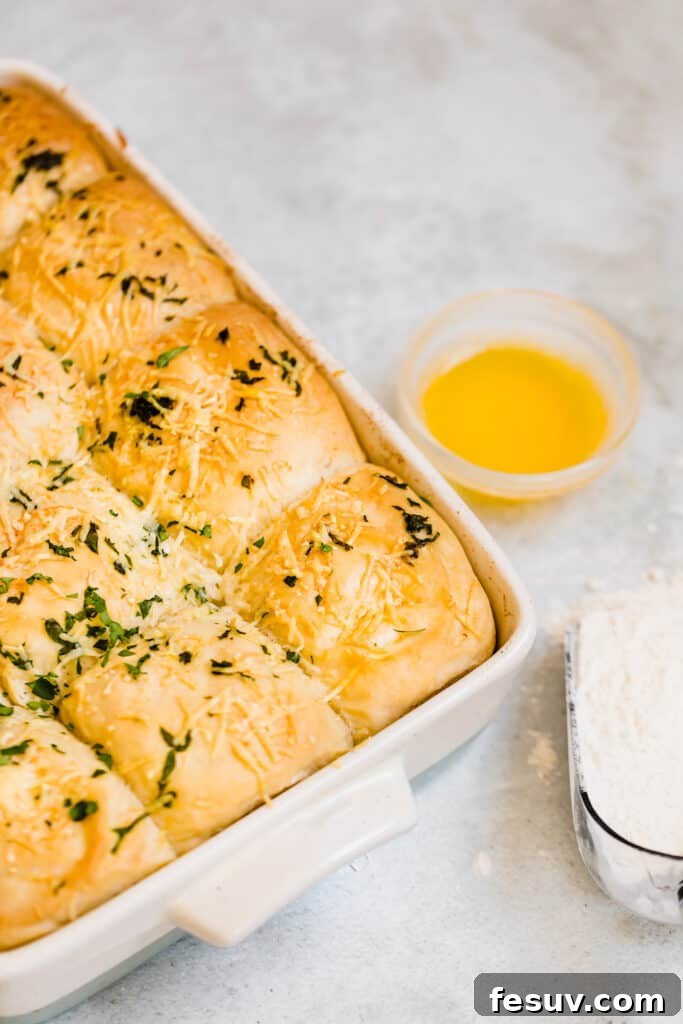 A large baking pan filled with golden-brown Soft Parmesan Dinner Rolls, showcasing their appealing texture