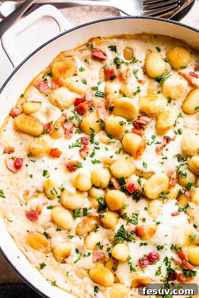 Ultimate Bacon Gnocchi Bake 2 Overhead shot of a bubbling Gnocchi and Bacon Casserole in a white baking dish, garnished with fresh chives.