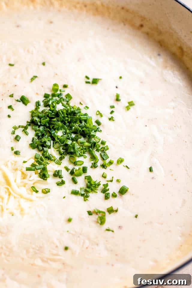 Ultimate Bacon Gnocchi Bake 5 Close-up of a skillet filled with creamy cheese sauce and chopped fresh chives, ready to be mixed with gnocchi and bacon.