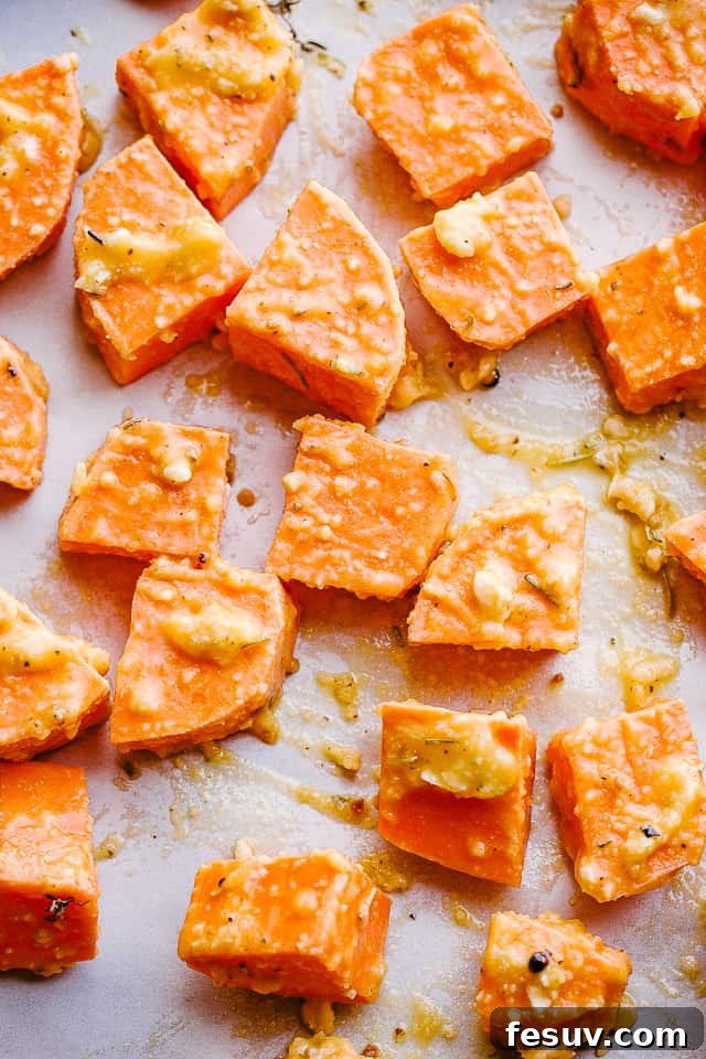Caramelized Garlic Honey Sweet Potatoes 2 Overhead shot of raw sweet potato cubes spread evenly on a parchment-lined baking sheet, prepared for roasting.