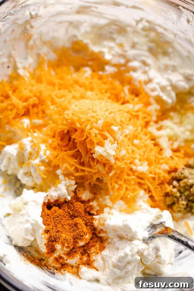 Mixing bowl with cream cheese, sour cream, mayonnaise, and seasonings, ready for mixing.