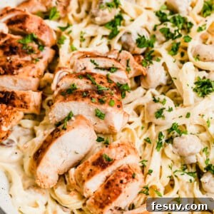 A Close-Up Shot of Sliced Chicken Breasts and Fettuccine Pasta with Alfredo Sauce