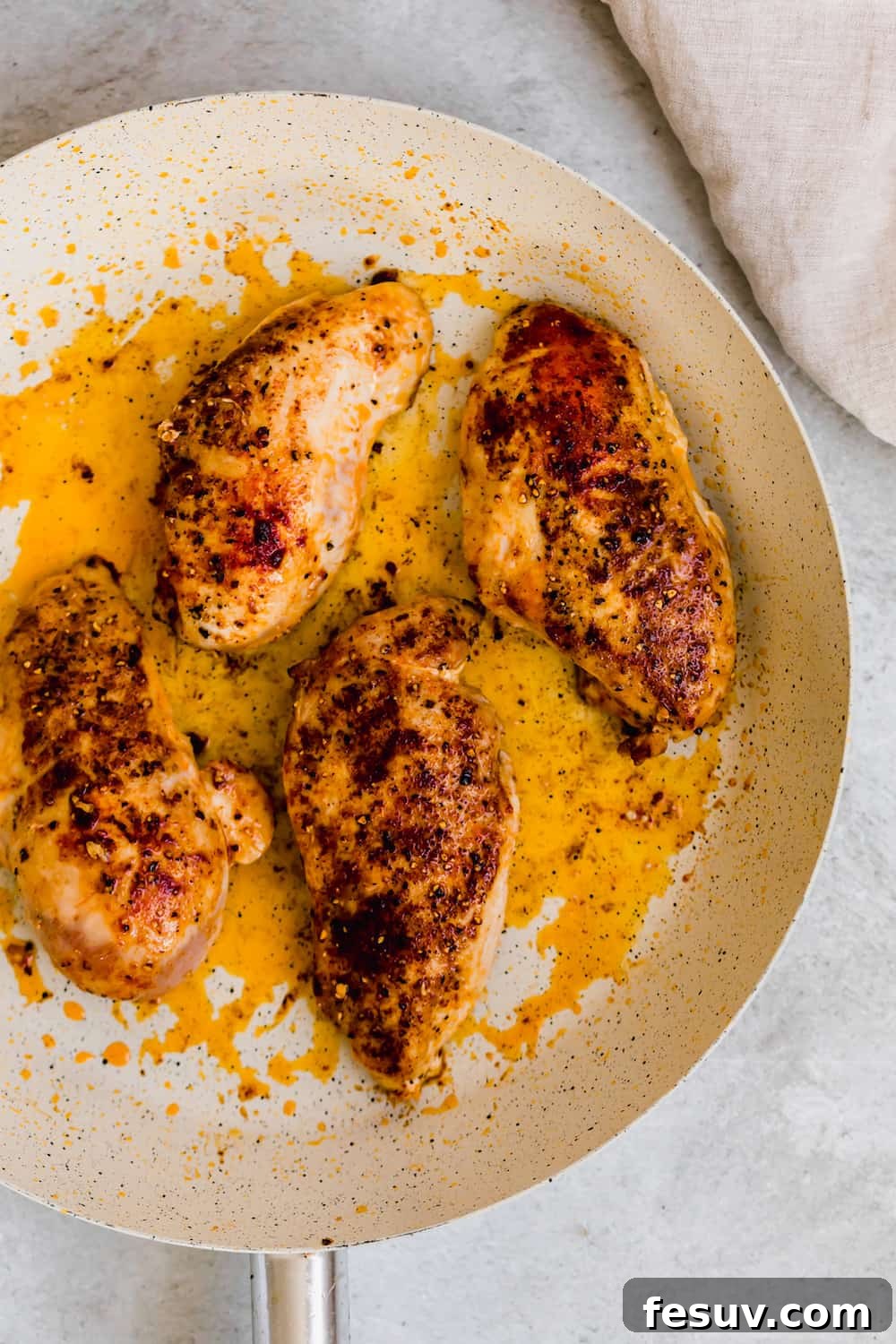 Four Cooked Chicken Breasts in a Black and White Skillet