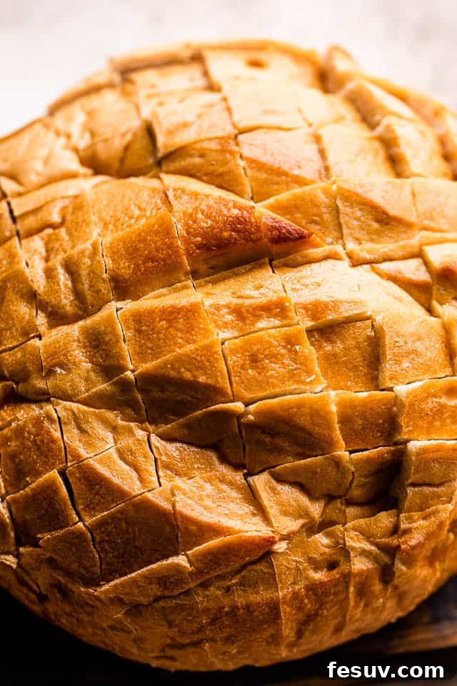 Ultimate Cheesy Garlic Sharing Loaf 3 round loaf of bread scored in a crosshatch pattern, ready for filling