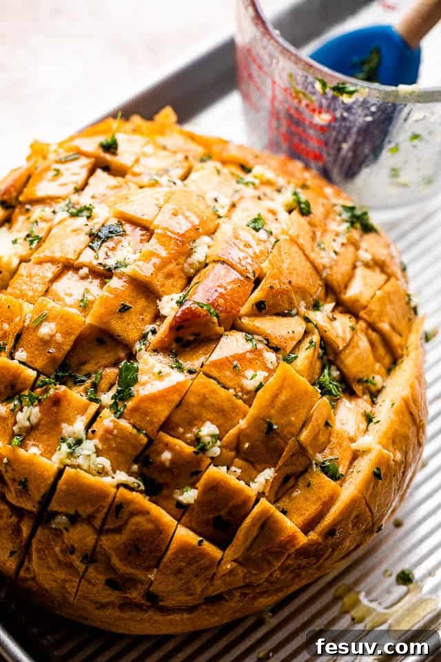 Ultimate Cheesy Garlic Sharing Loaf 5 crosshatched loaf of bread with melted butter, garlic, and parsley before baking