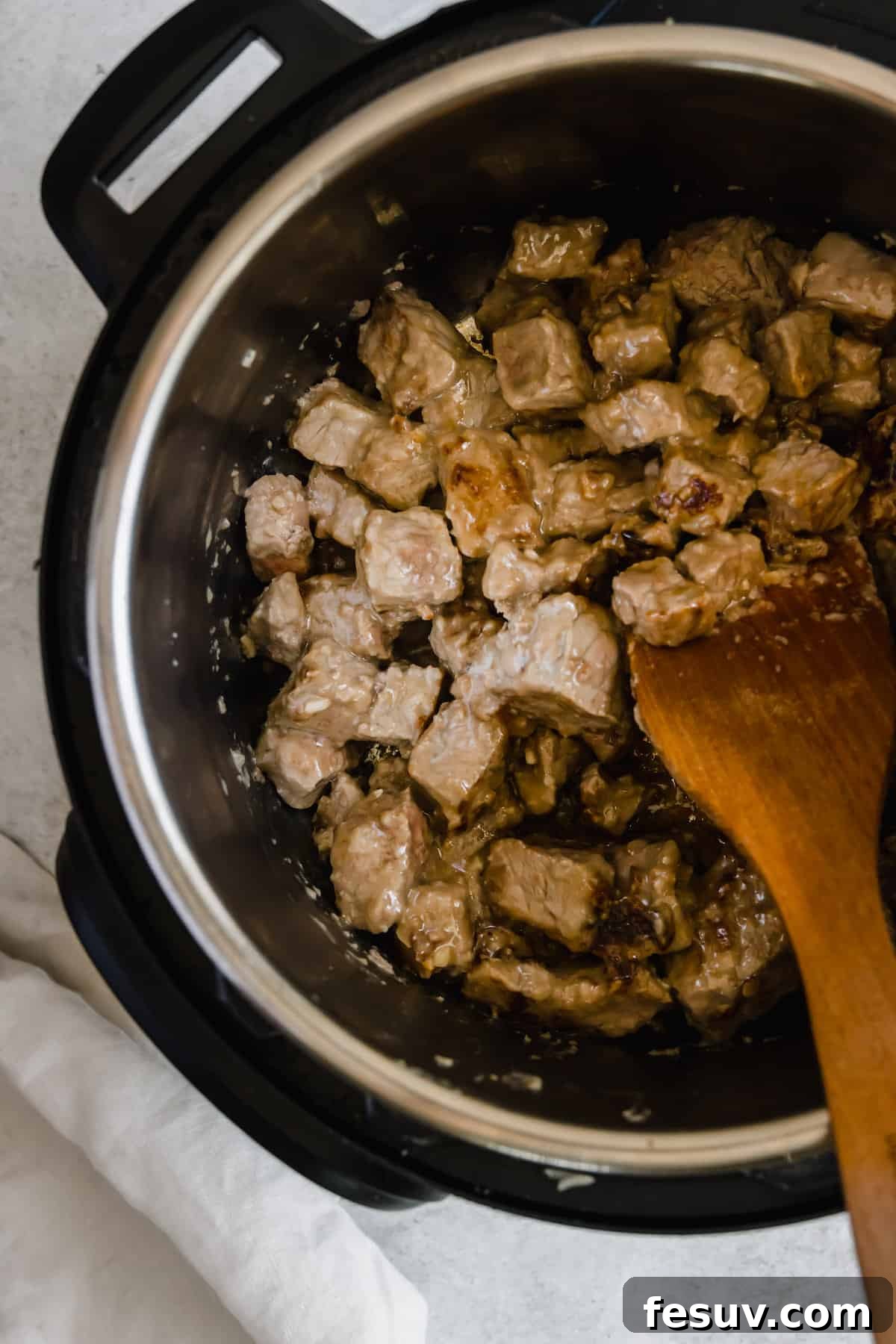 Effortless Creamy Instant Pot Beef Stroganoff 8 Beef Being Stirred Around in the Instant Pot by a Wooden Spoon, as it browns to perfection.