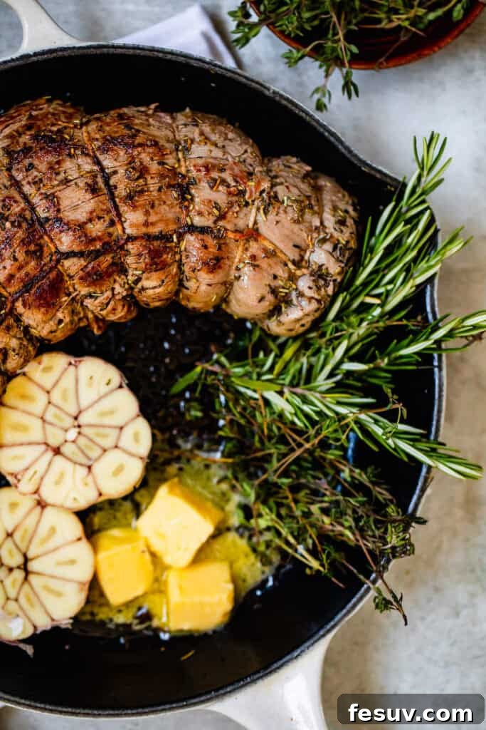 Melted butter simmering in a saucepan with a roast beef tenderloin and sprigs of fresh rosemary, creating a flavorful basting liquid.