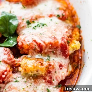 Crispy Pork Parmesan 7 close up side shot of baked pork parmigiana topped with melted cheese and basil leaves.