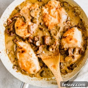 Rich Creamy Chicken Marsala 12 Chicken in a creamy marsala sauce with a wooden serving spoon.