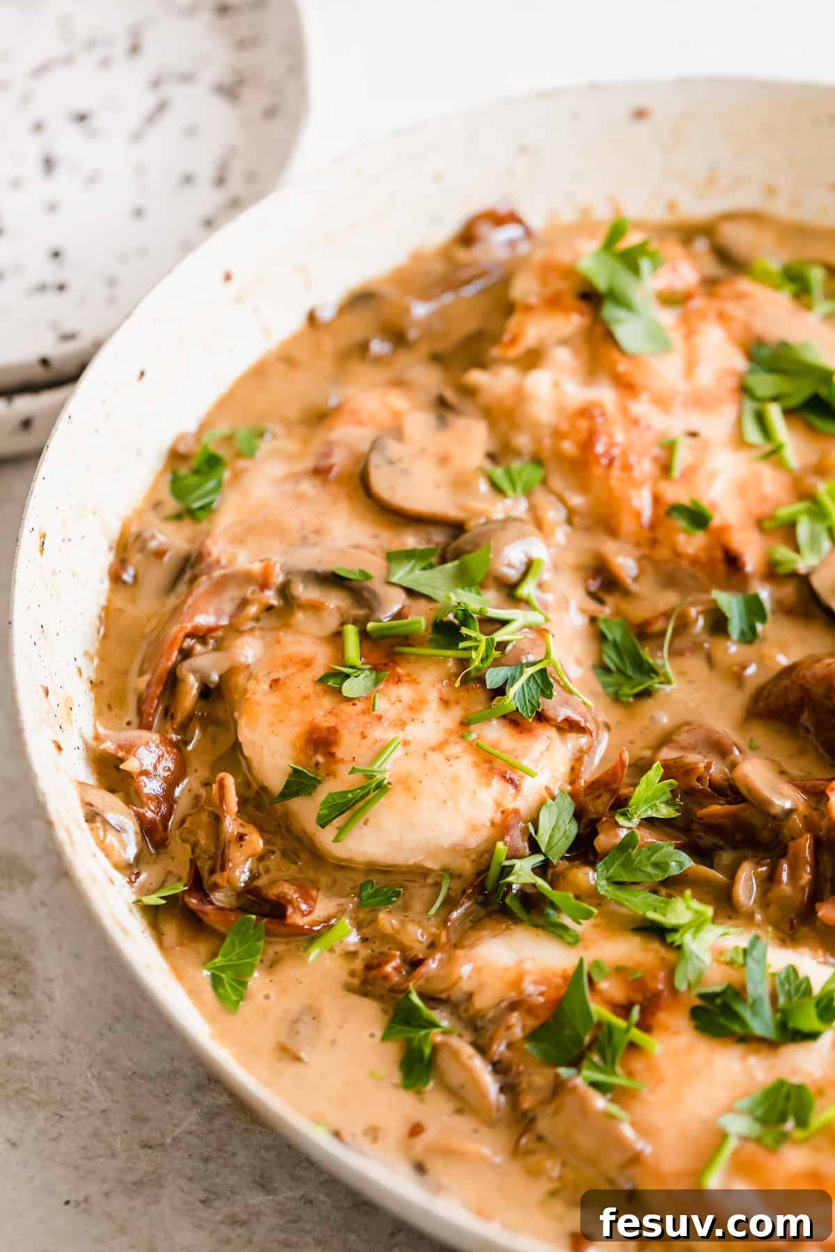 Rich Creamy Chicken Marsala 10 Creamy chicken marsala in a white bowl sprinkled with herbs.