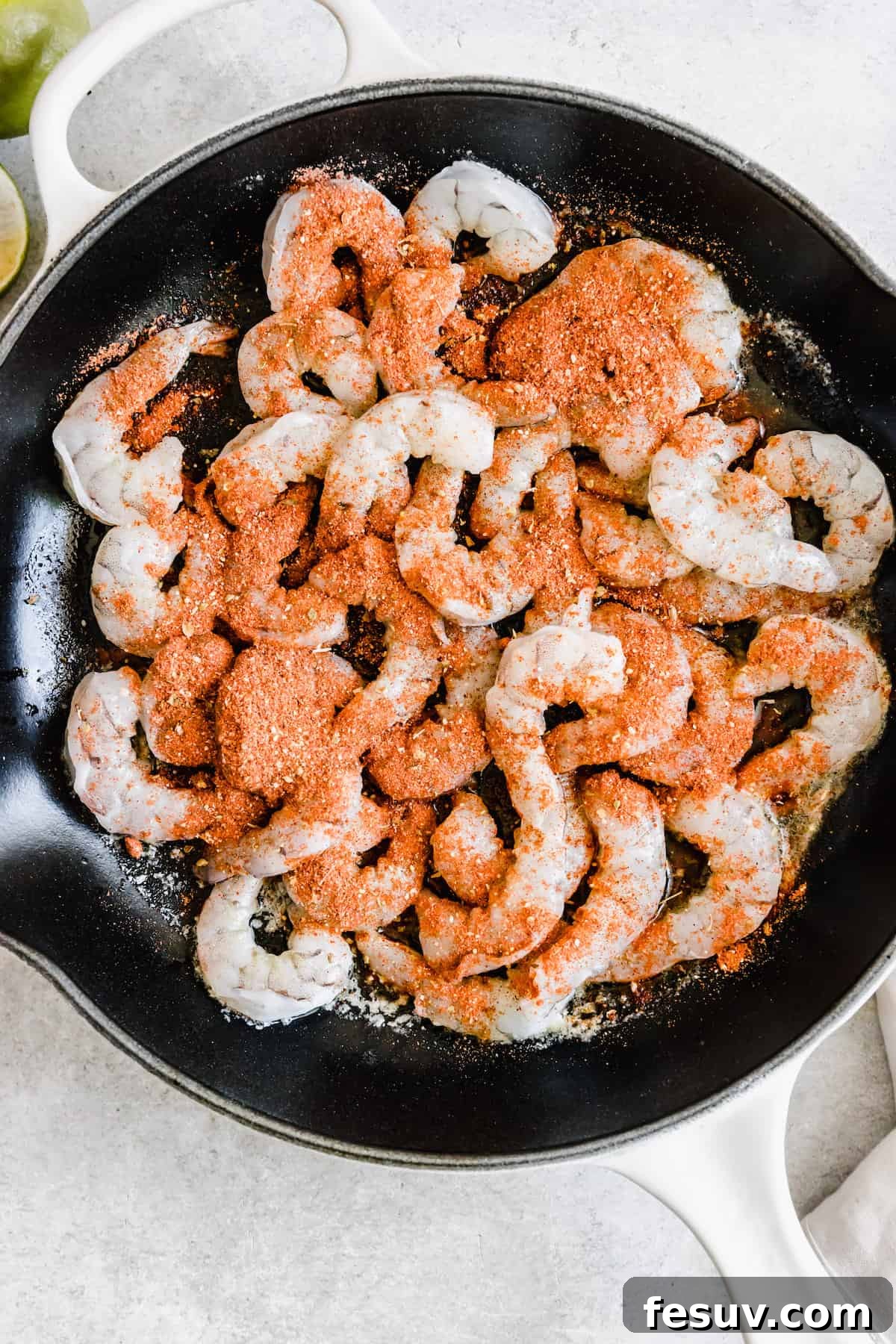 My easy shrimp tacos recipe with Asian cabbage slaw is guaranteed to be a new favorite. The classic flavors of a warm shrimp taco blend amazingly with the fresh, crunchy slaw in warm tortillas! Seasoned Shimp Inside of a Metal Skillet