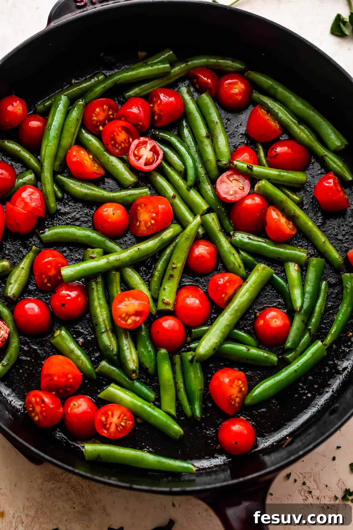 Bayou Blackened Chicken Pasta 6 overhead shot of pan frying cherry tomatoes and green beans in a cast iron skillet