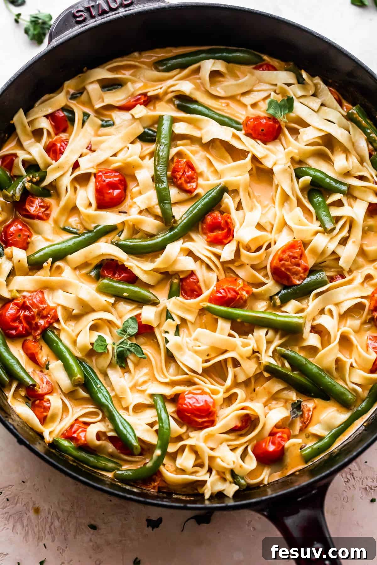 Bayou Blackened Chicken Pasta 8 overhead shot of a skillet with fettuccine pasta in creamy sauce with tomatoes, and green beans
