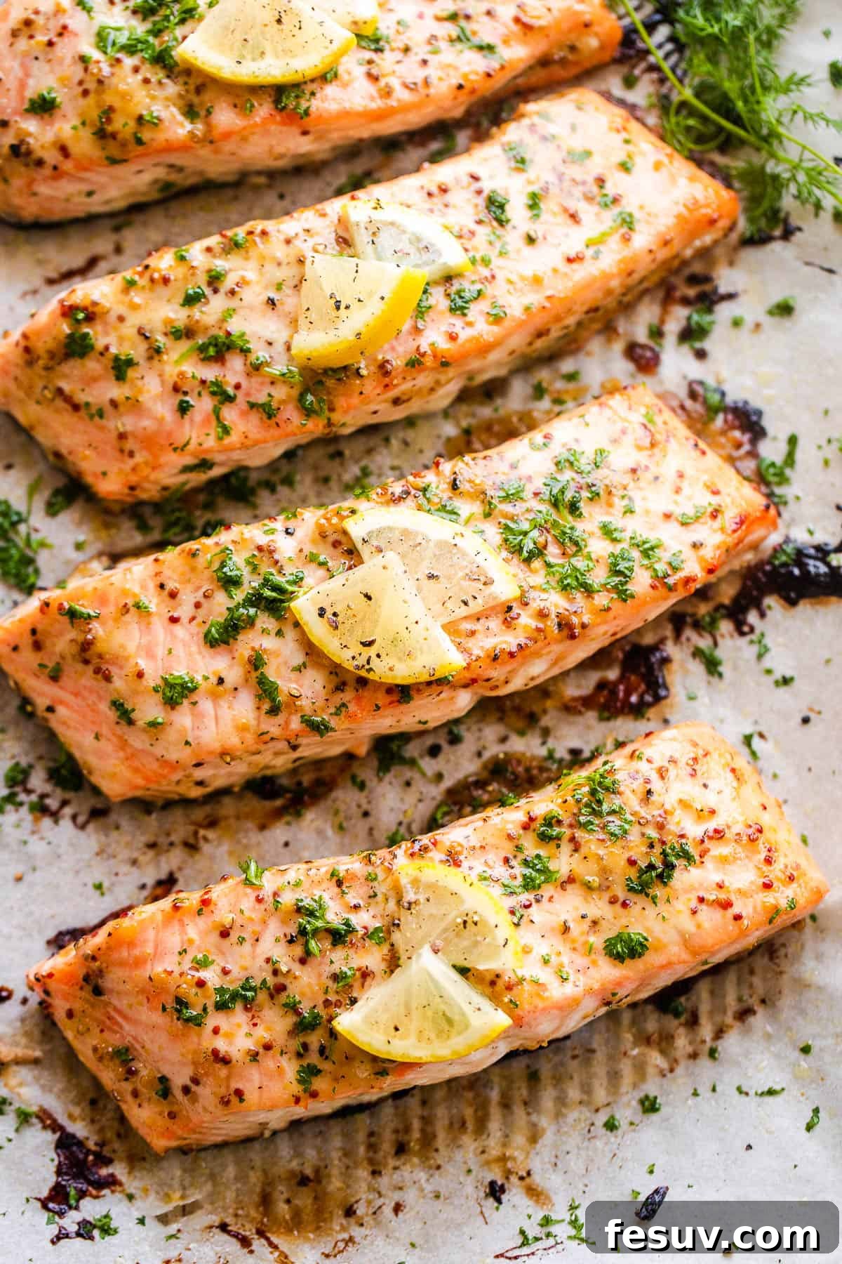 This baked Maple Mustard Salmon recipe is lightly seasoned, then brushed with a sweet and tangy sauce made from maple syrup and Dijon mustard! Four perfectly baked maple mustard salmon fillets, golden-brown and glazed, arranged on a baking sheet.