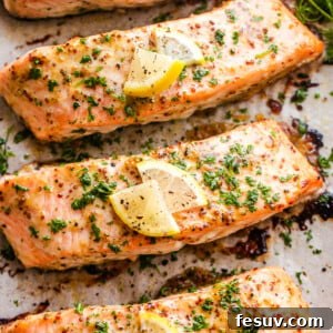 Four baked maple mustard salmon fillets on a baking sheet