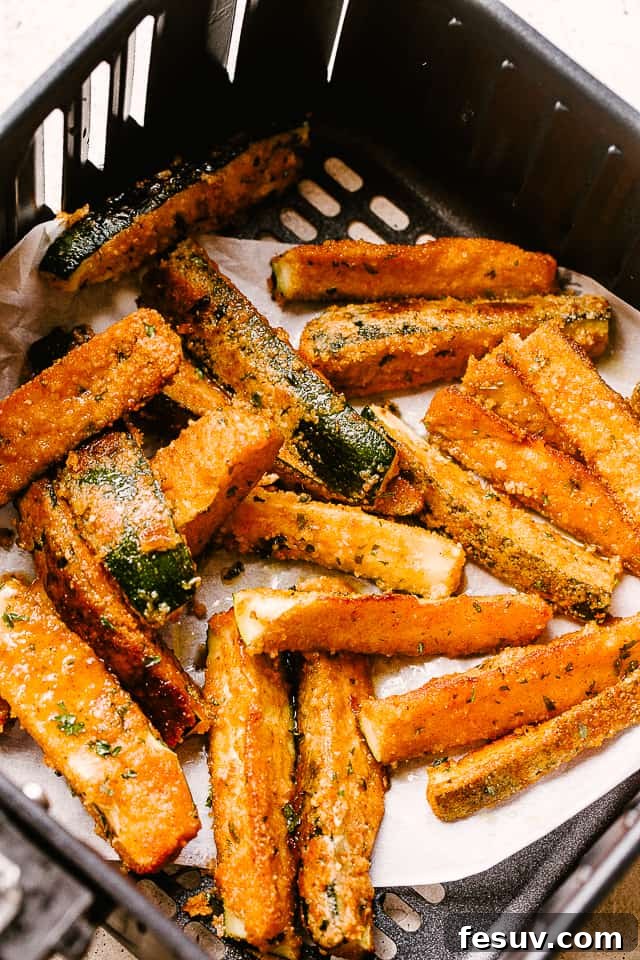 These air fryer zucchini fries are super crispy on the outside, tender on the inside, and perfect for dipping. Your go-to summer side dish! Fried zucchini in the basket of an air fryer.