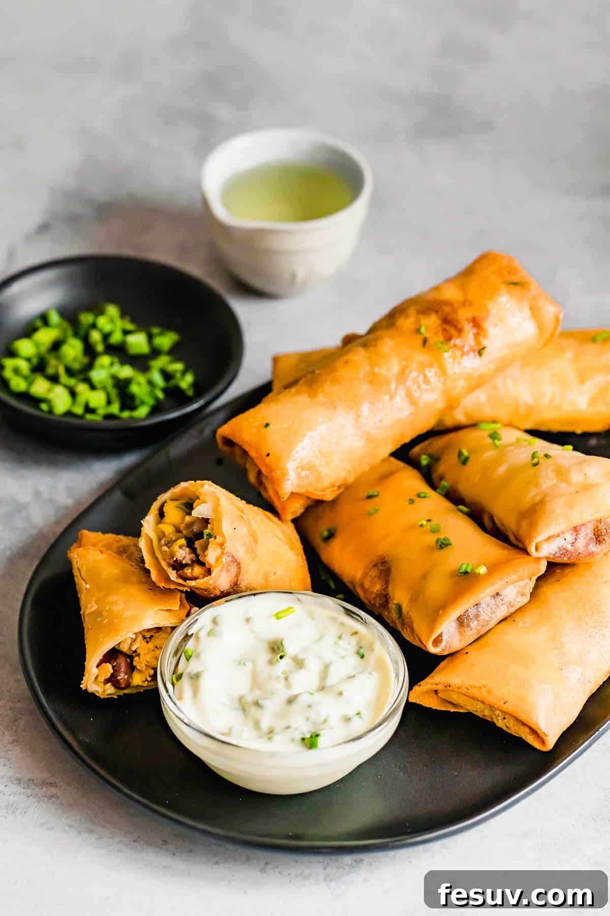 A Plate of Egg Rolls with a Glass Dish of Dipping Sauce