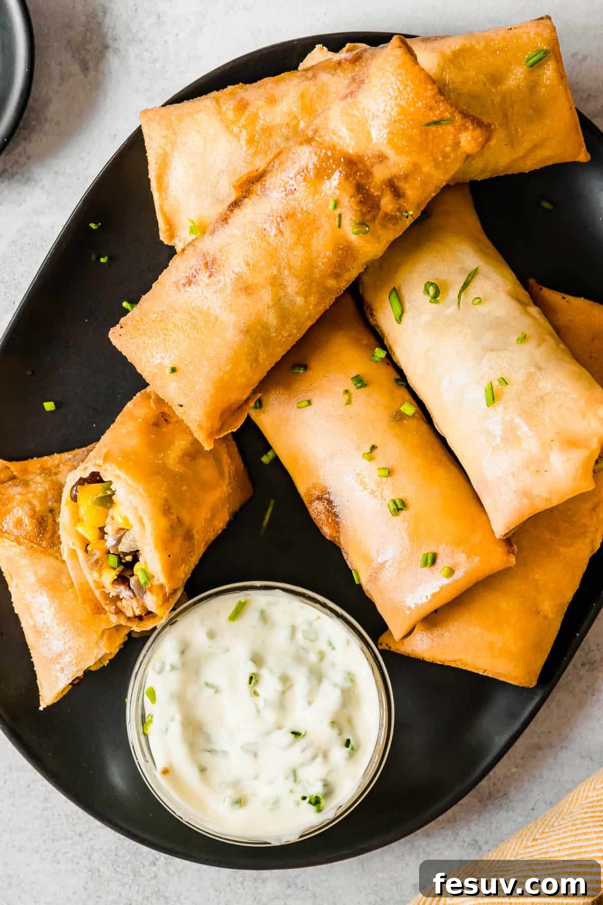 A Plate of Egg Rolls with a Glass Dish of Dipping Sauce