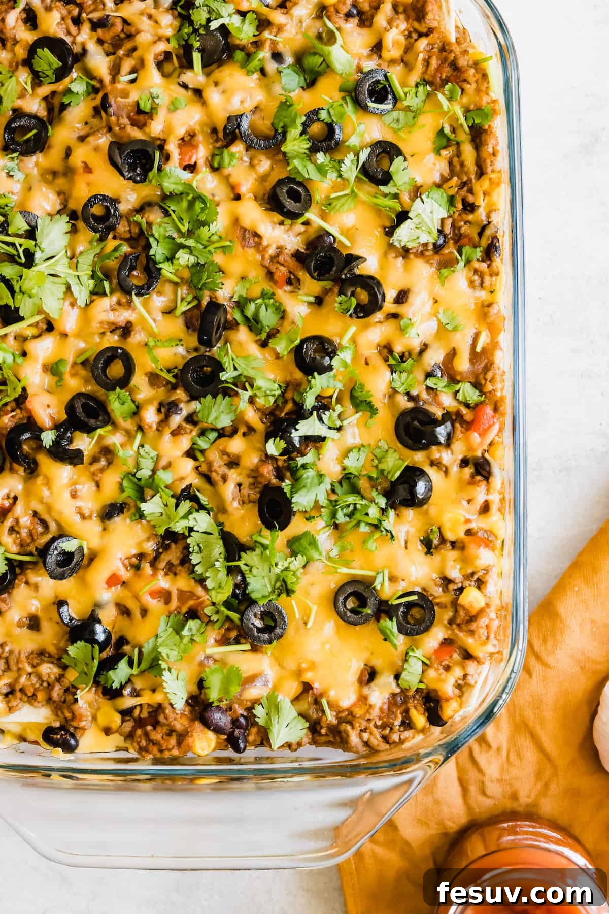 Enchilada Lasagna 11 A delicious glass casserole dish filled with baked Mexican Lasagna, resting on a countertop, steaming slightly.