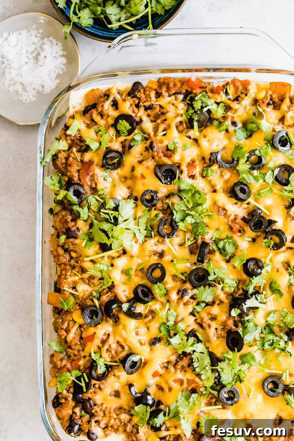 Enchilada Lasagna 3 A vibrant Mexican Lasagna Casserole in a clear glass baking dish, showing visible layers of filling and tortillas.