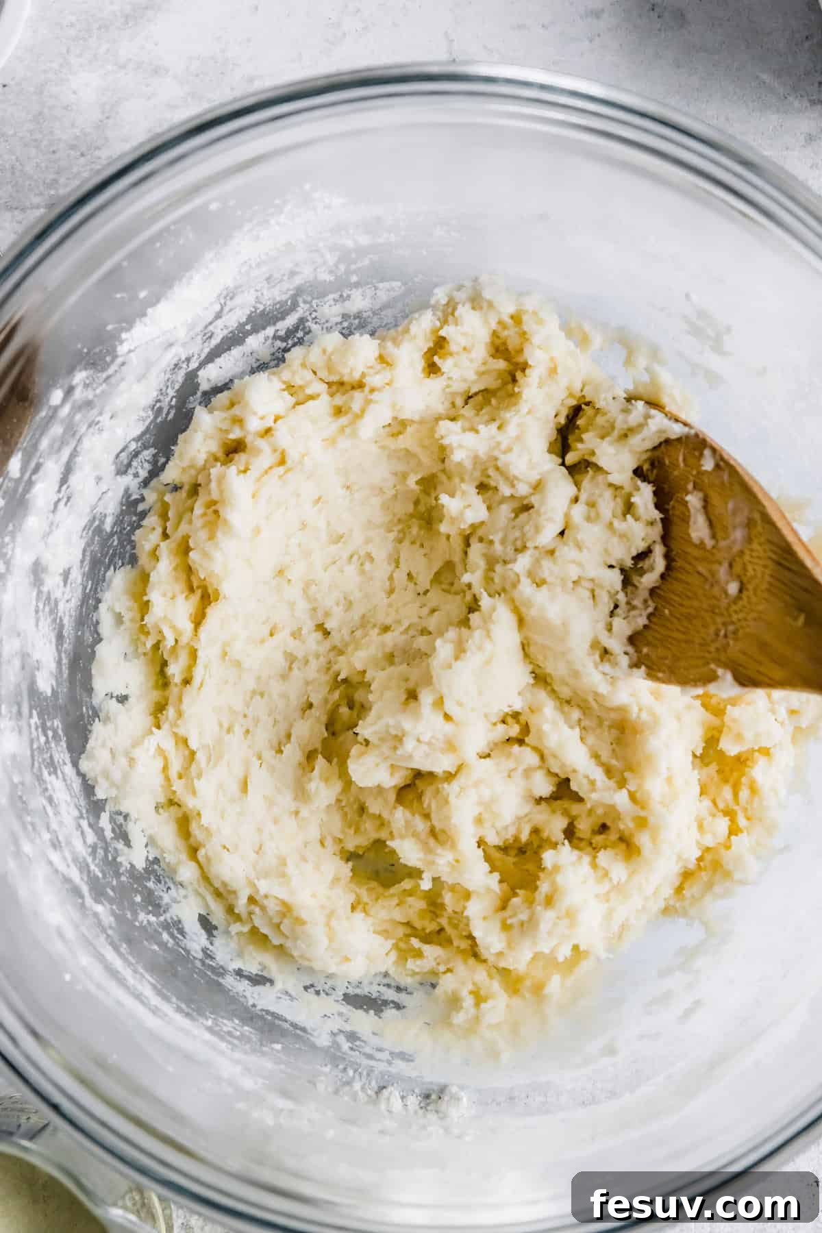 Perfect Homemade Churros 5 Churro dough in a large glass mixing bowl, showcasing its thick and sticky consistency.