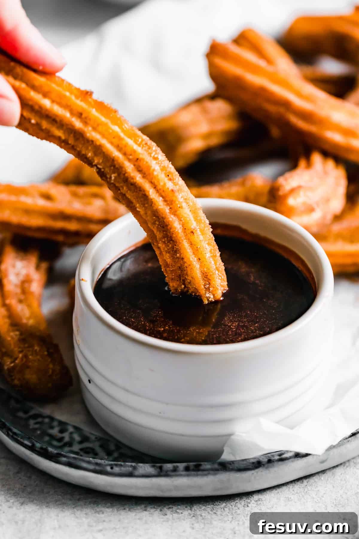 Perfect Homemade Churros 9 A churro being dipped into a rich chocolate sauce, highlighting the perfect pairing.