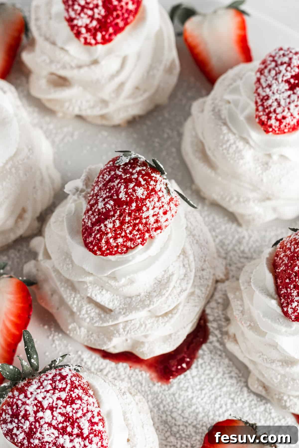 Pavlovas topped with strawberries and powdered sugar