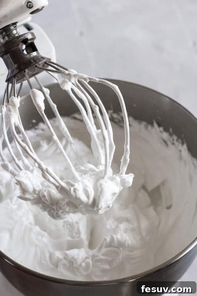 The whisk of a stand mixer with whipped meringue