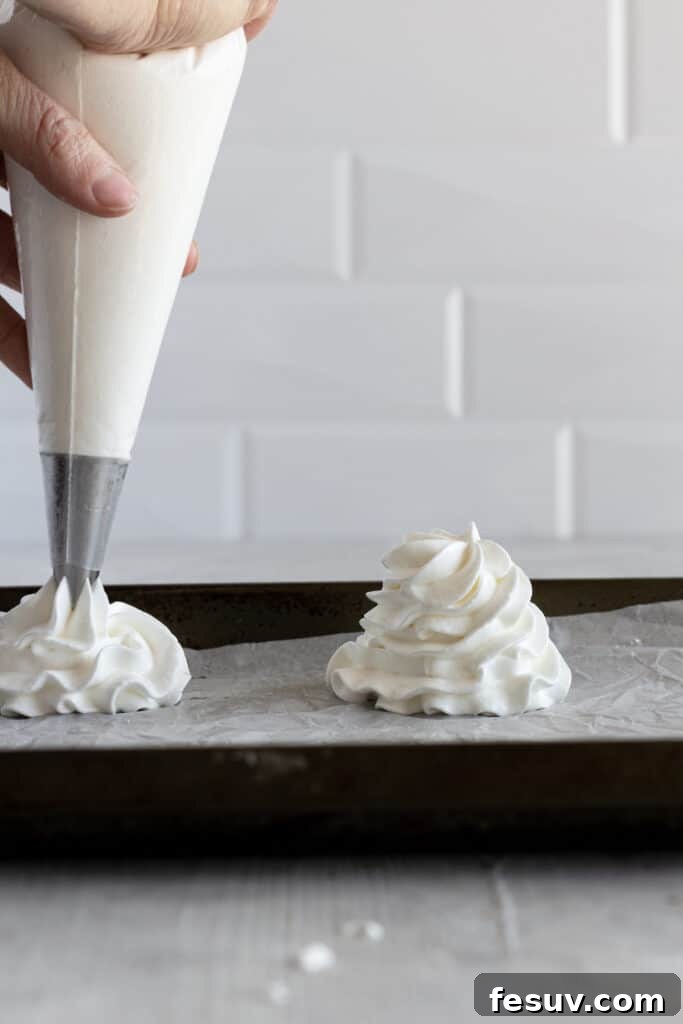 Piping bag pipping pavlova nests onto a baking sheet