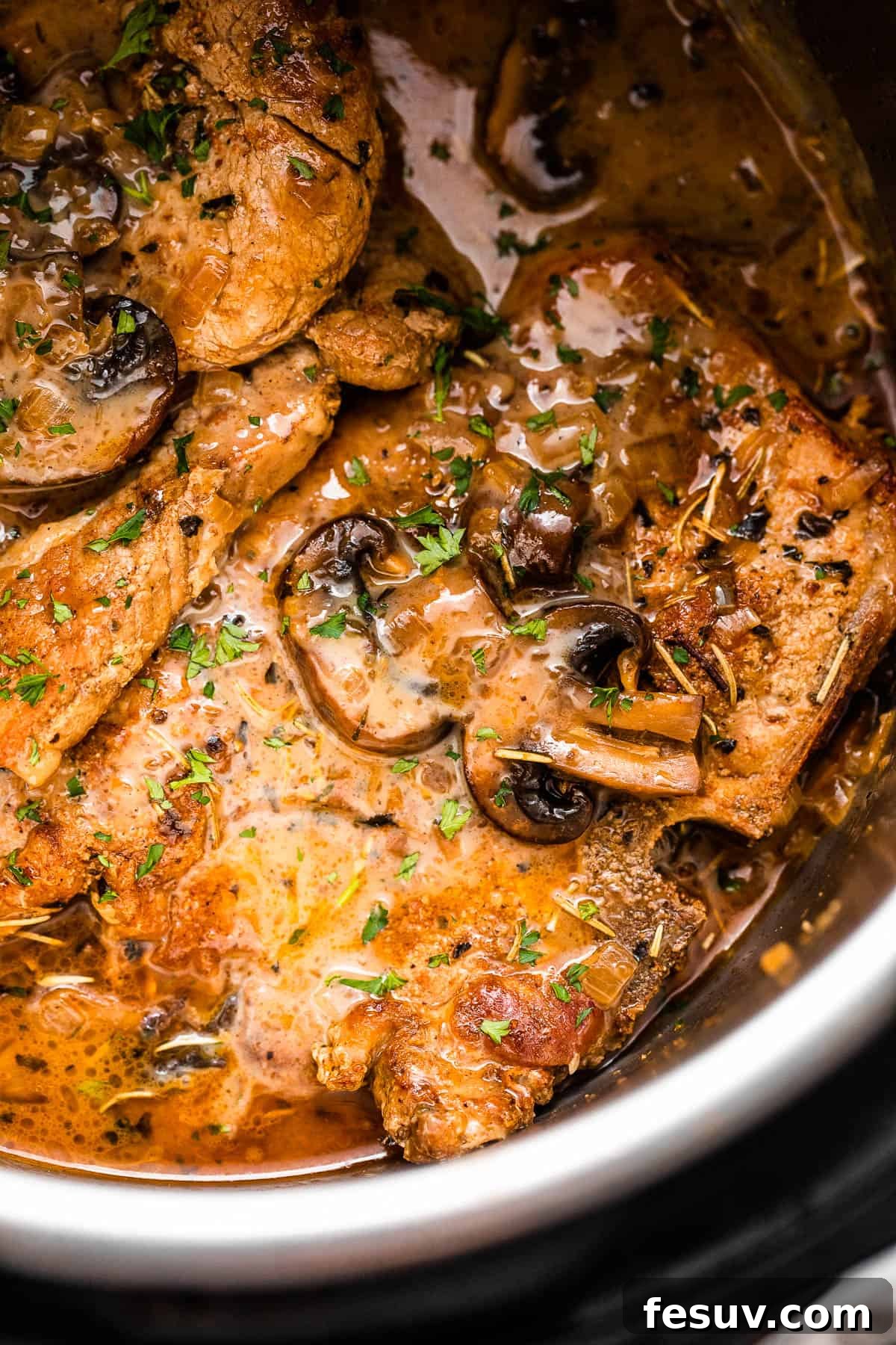 Perfectly Tender Instant Pot Pork Chops 2 Close-up shot of perfectly cooked pork chops in the Instant Pot, generously topped with a rich creamy mushroom gravy sauce, ready to be served.