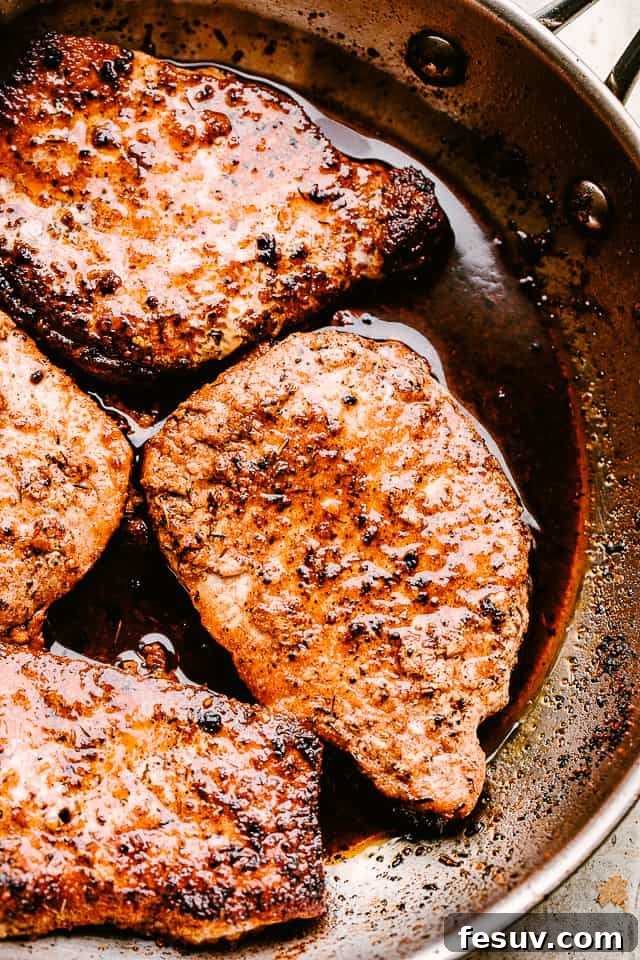 Juicy, tender, and flavorful, these garlic parmesan pan fried pork chops are smothered in a rich honey garlic sauce. Done in just 20 minutes! Close-up of golden brown pan-fried pork chops in a skillet, ready for covering.