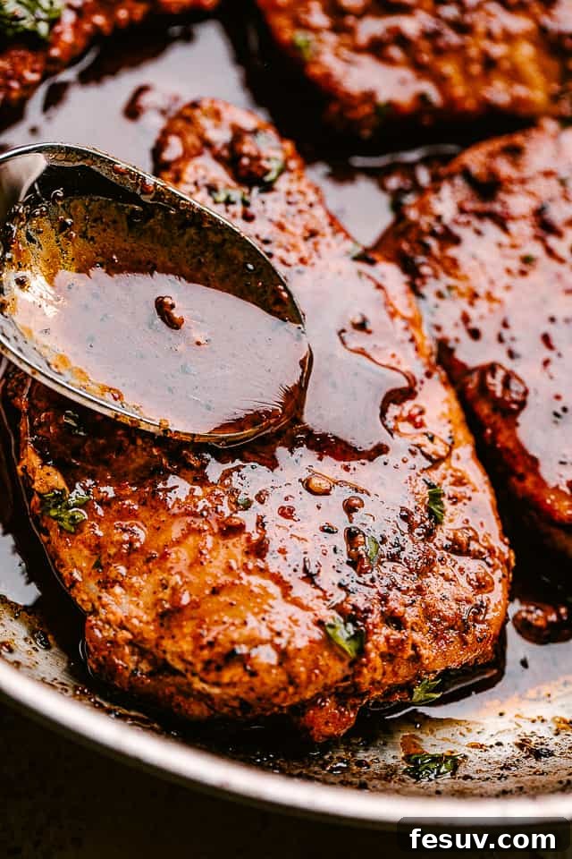 Juicy, tender, and flavorful, these garlic parmesan pan fried pork chops are smothered in a rich honey garlic sauce. Done in just 20 minutes! Close-up of a skillet filled with juicy pan-fried pork chops coated in a rich honey garlic sauce, garnished with fresh herbs.