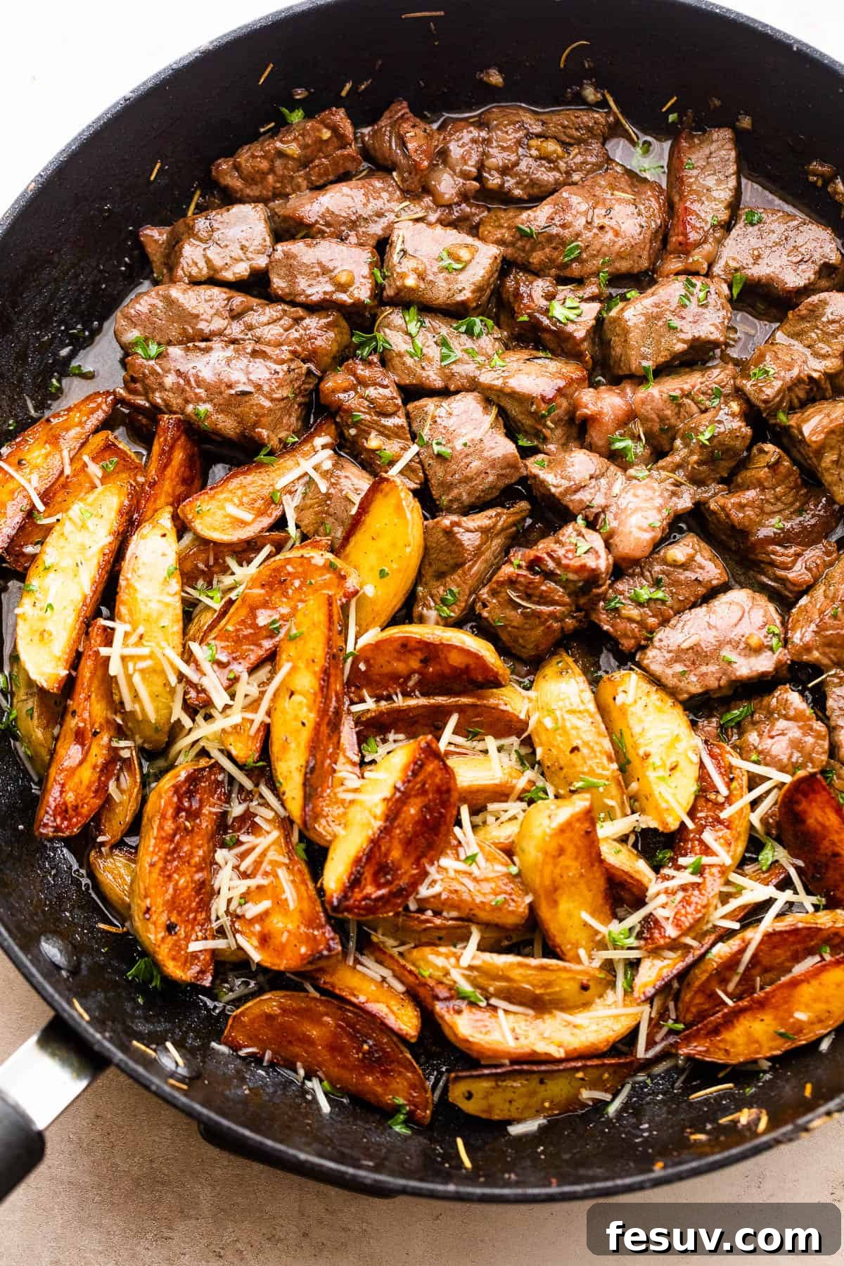Cubed sirloin steak and quartered gold baby potatoes cooking together in a cast iron skillet, golden brown and tender
