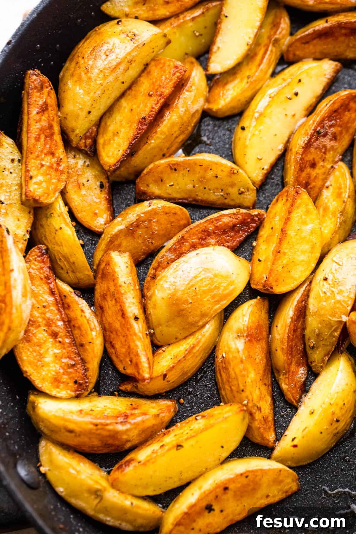 Close-up of quartered gold baby potatoes sizzling and browning in a hot cast iron skillet