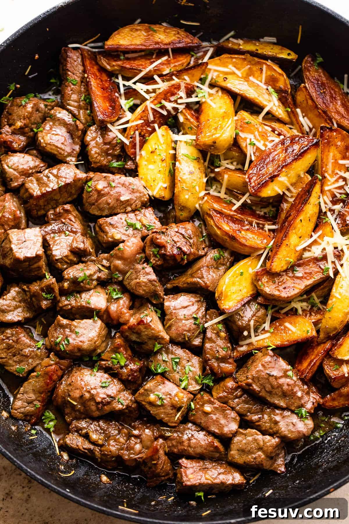 Overhead shot of perfectly seared sirloin steak bites and golden brown quartered potatoes plated directly from the skillet