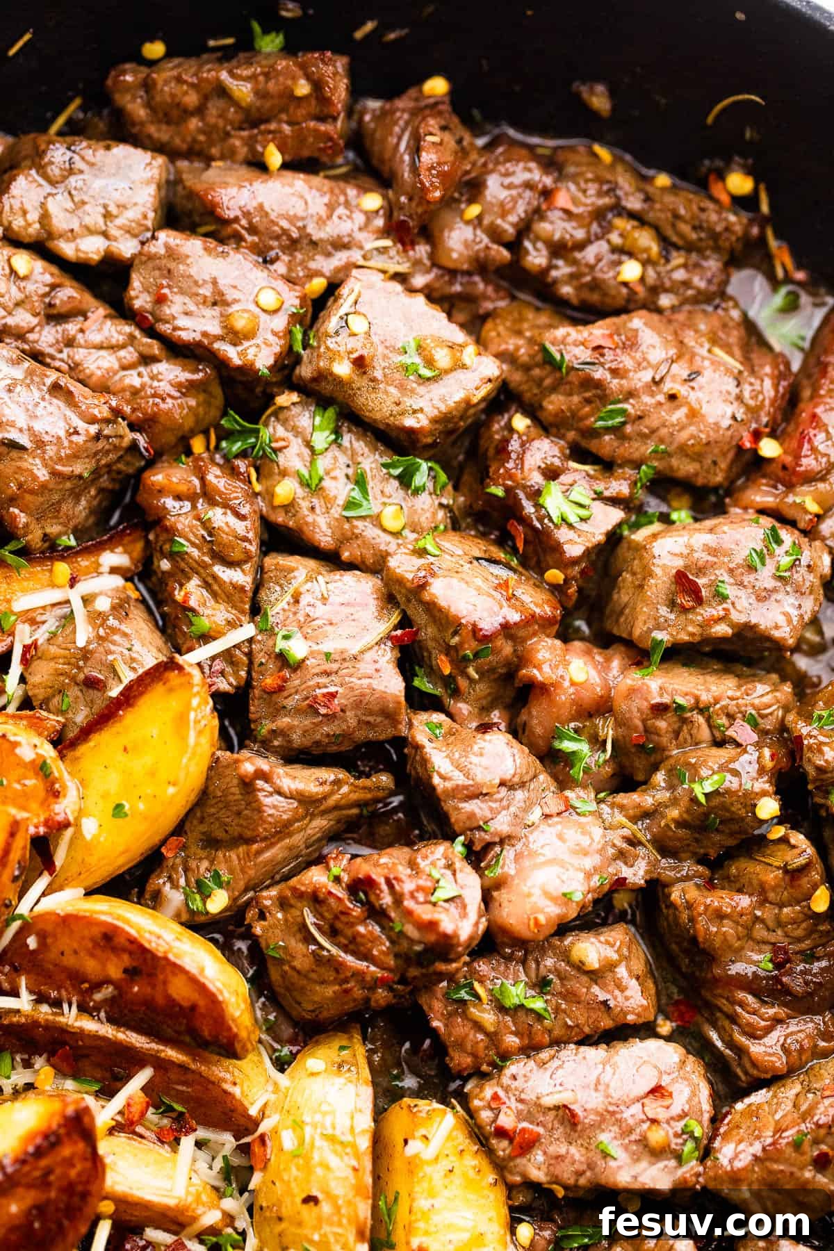 Close-up of cubed sirloin steak bites sizzling in a hot cast iron skillet, developing a dark brown crust