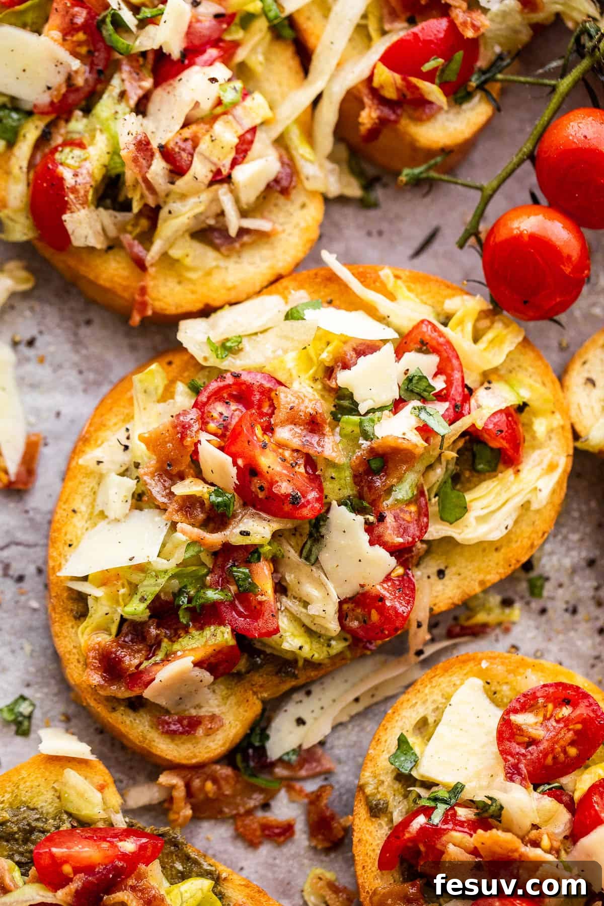 Freshly assembled BLT Bruschetta, topped with bacon, lettuce, and tomato salad, on a white plate