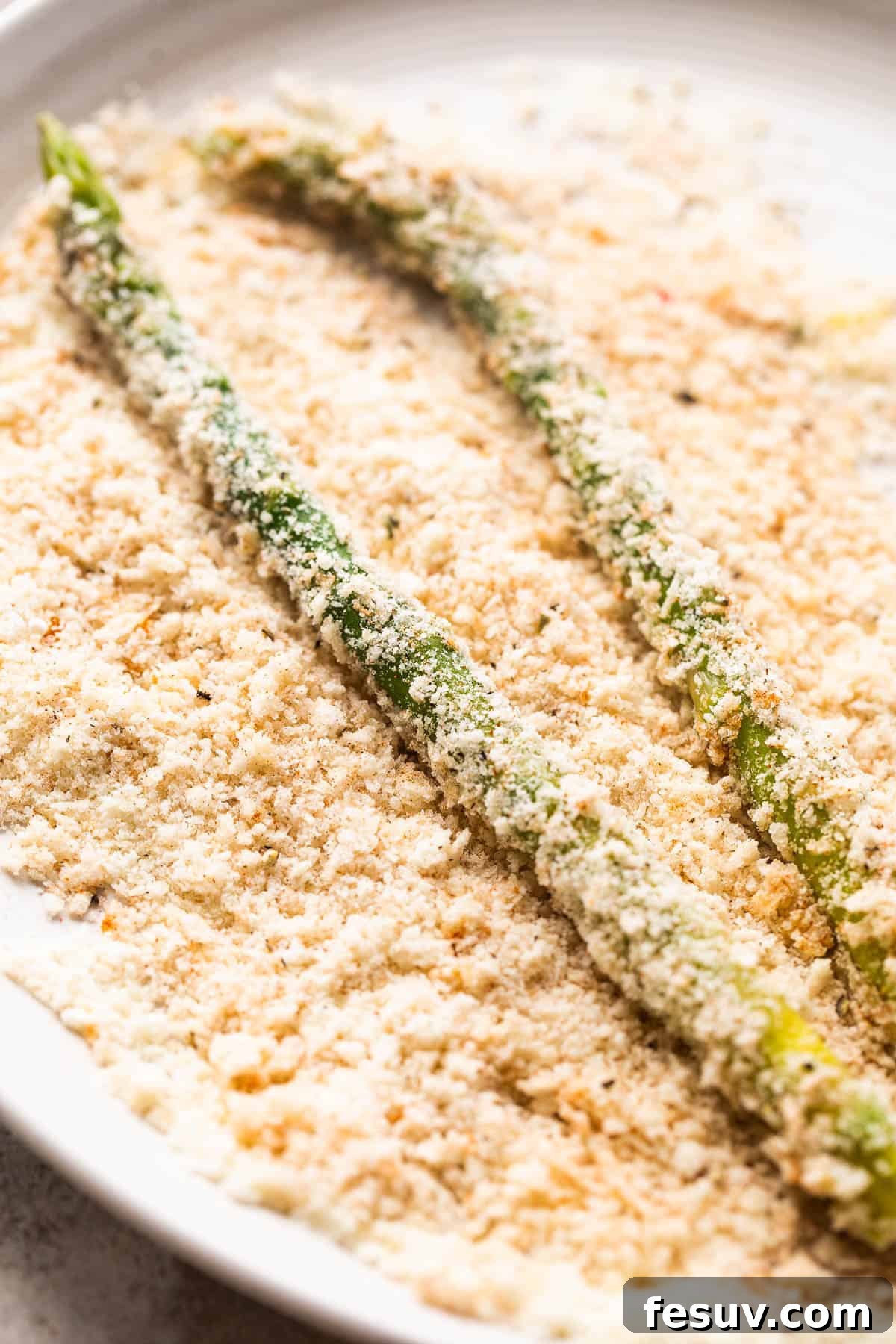 rolling fresh asparagus spears in panko bread crumb mixture
