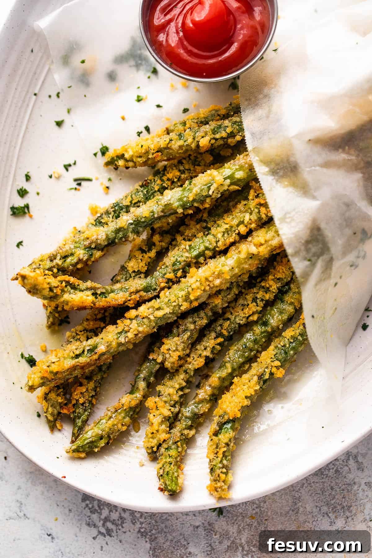 overhead shot of baked parmesan panko asparagus fries served with ketchup on the side